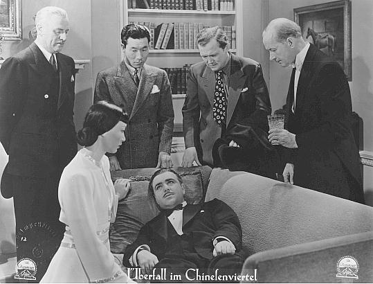 Philip Ahn, Anna May Wong, and others surround the ailing Akim Tamirov in this publicity still for the German release of King of Chinatown